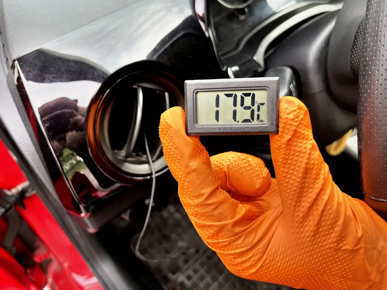 Rękawiczka w ręku trzyma termometr pokazujący 17.9°C. To część procesu samodzielnego nabijania klimatyzacji w samochodzie.