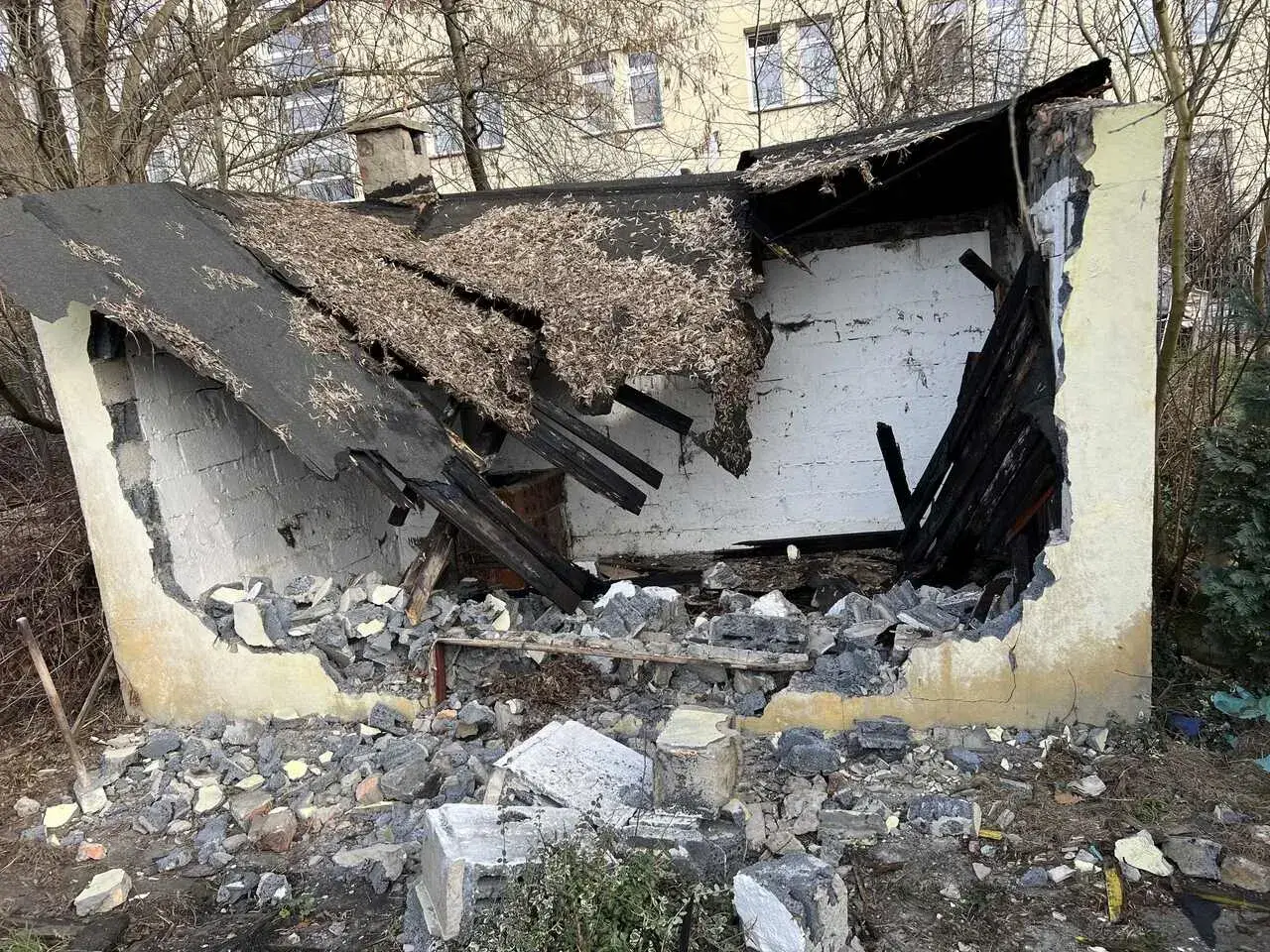 Zniszczony budynek, dach się zawalił, gruzy na ziemi. Trwa rozbiórka.