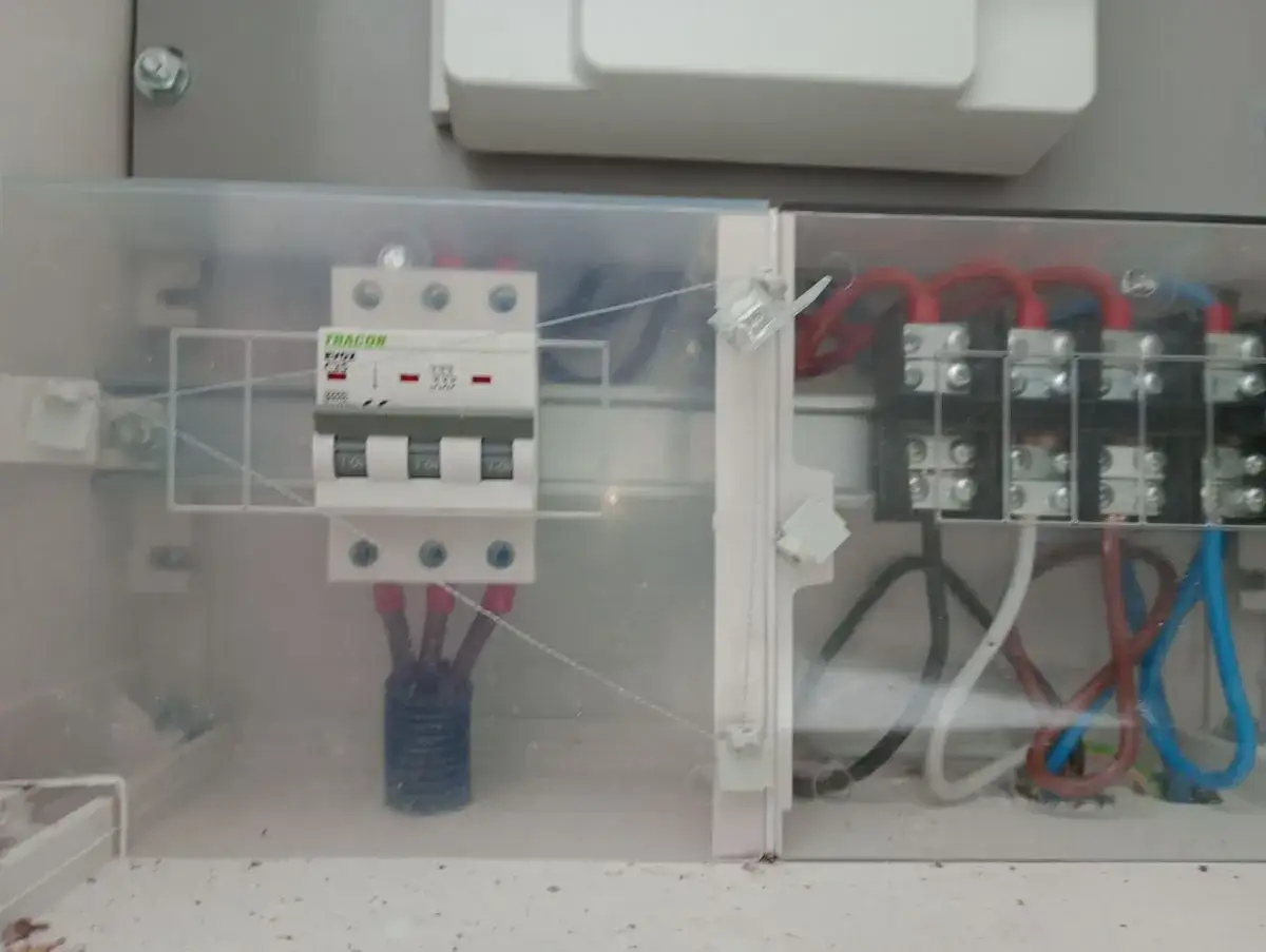W skrzynce elektrycznej widoczny jest zabezpieczenie przedlicznikowe Tracon, połączone z innymi przewodami.