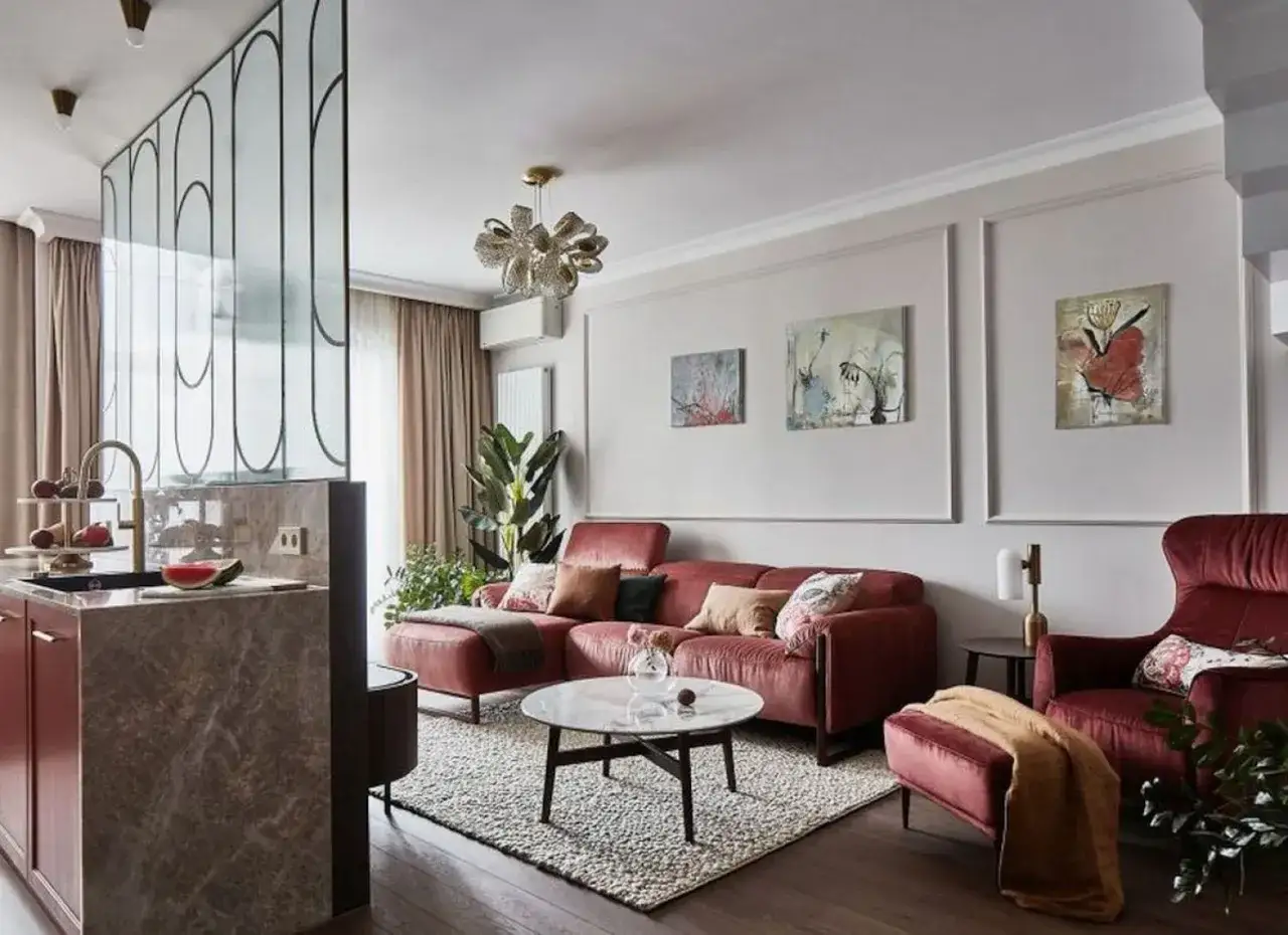 Elegancki salon z czerwoną kanapą i fotelami. Jasne, neutralne kolory ścian do salonu podkreślają ciepło i przytulność wnętrza.