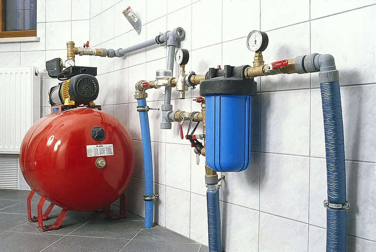 Nowoczesna hydrofornia z czerwonym zbiornikiem i niebieskim filtrem wody.